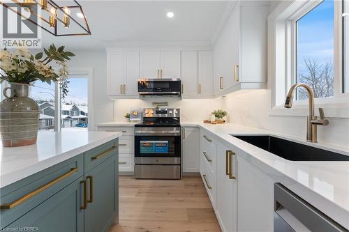 Bright & modern design with quartz countertop & backsplash, contrasting island, pot-filler, and stainless steel appliances. - 50 Fife Street W, Caledonia, ON - Indoor Photo Showing Kitchen With Upgraded Kitchen
