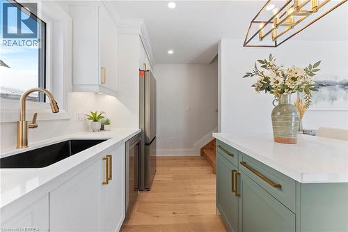 Bright & modern design with quartz countertop & backsplash, contrasting island, pot-filler, and stainless steel appliances. - 50 Fife Street W, Caledonia, ON - Indoor Photo Showing Kitchen With Upgraded Kitchen