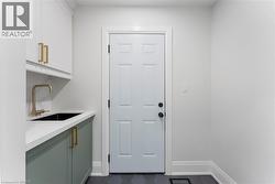 Main floor laundry with inside entry from garage. Built-in sink with quartz countertop and storage closet. - 