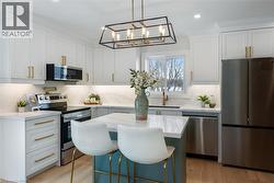 Bright & modern design with quartz countertop & backsplash, contrasting island, pot-filler, and stainless steel appliances. - 