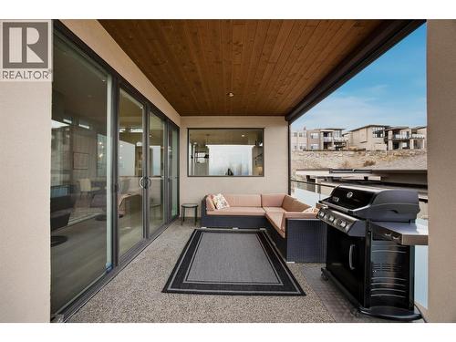 Main floor balcony features covered & uncovered lounge areas, wood soffits, glass railings, exposed aggregate, a gas hookup & automatic sunshades - 468 Sparrow Hawk Court, Kelowna, BC - Outdoor With Exterior