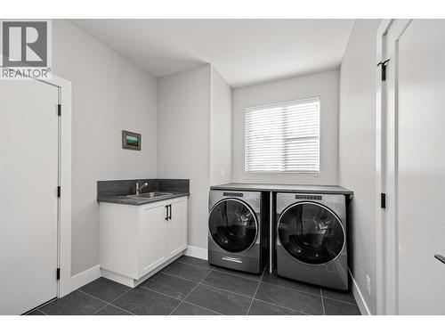 Laundry/Mud room featuring an Arborite counter, stainless steel sink, Whirlpool washer and dryer and a bright window overlooking the front yard - 468 Sparrow Hawk Court, Kelowna, BC - Indoor Photo Showing Laundry Room