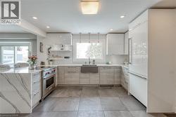 Kitchen with high end appliances, light stone countertops, modern cabinets, open shelves, and recessed lighting - 