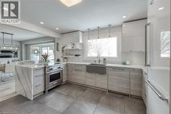 Kitchen featuring hanging light fixtures, light stone countertops, high end appliances, a peninsula, and recessed lighting - 