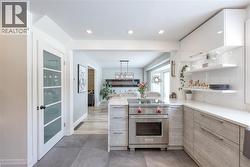 Kitchen with modern cabinets, a peninsula, designer range, open shelves, and decorative light fixtures - 