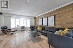 Living room featuring ornamental molding, wood walls, a wood stove, light wood-type flooring, and a textured ceiling - 