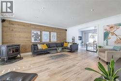Living room with wood walls, a wood stove, hardwood / wood-style flooring, a textured ceiling, and an accent wall - 
