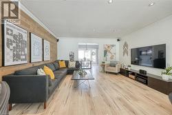 Living area featuring wood walls, ornamental molding, a textured ceiling, light wood-style floors, and an accent wall - 