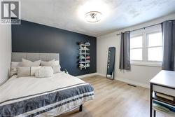 Bedroom with light wood-style flooring, a textured ceiling, and an accent wall - 