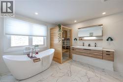 Bathroom featuring a sauna / steam room, double vanity, light marble finish flooring, a freestanding tub, and recessed lighting - 