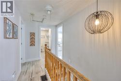 Corridor with an upstairs landing, light wood-style flooring, a textured ceiling, and attic access - 