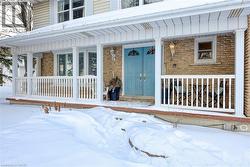Snow covered property entrance with a porch and brick siding - 