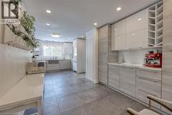 Kitchen featuring open shelves, modern cabinets, white cabinets, backsplash, and light stone counters - 