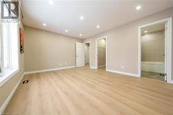 Unfurnished bedroom with a spacious closet, light wood finished floors, recessed lighting, and connected bathroom - 