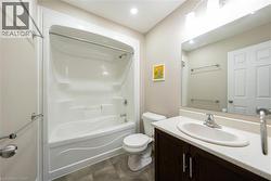 Bathroom with vanity, bathing tub / shower combination, dark tile patterned floors, and recessed lighting - 