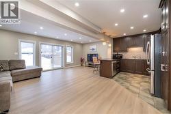 Kitchen with open floor plan, hanging light fixtures, a peninsula, dark brown cabinetry, and recessed lighting - 