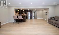 Kitchen with open floor plan, a peninsula, a kitchen bar, stainless steel appliances, and light wood-style floors - 