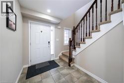 Foyer featuring stairs and light tile patterned floors - 