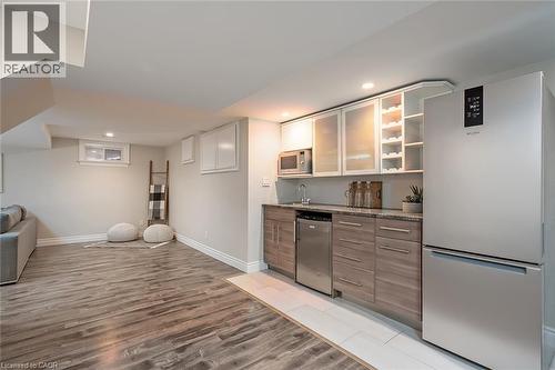 Bar area with appliances with stainless steel finishes, open shelves, light wood-style flooring, recessed lighting, and brown cabinetry - 4226 Dunvegan Road, Burlington, ON - Indoor