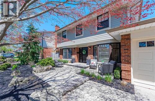 View of front of home with brick siding, a patio area, a chimney, and an outdoor living space - 4226 Dunvegan Road, Burlington, ON - Outdoor With Deck Patio Veranda