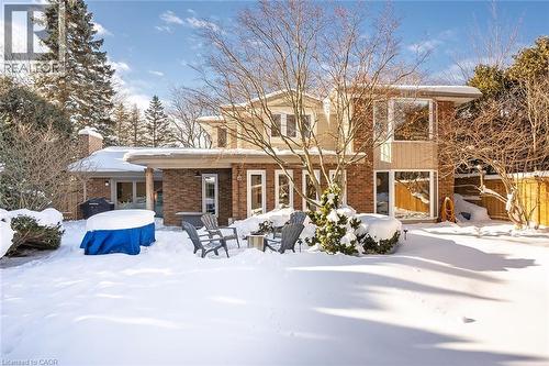 Snow covered back of property with brick siding, a chimney, and a patio - 4226 Dunvegan Road, Burlington, ON - Outdoor