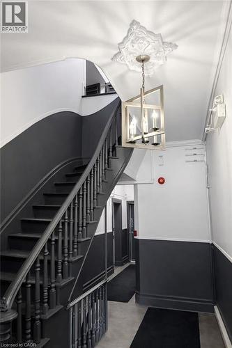 Stairway featuring a chandelier, crown molding, and concrete floors - 46 College Street, Kitchener, ON - Indoor Photo Showing Other Room