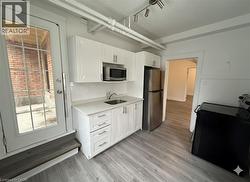 Kitchen featuring stainless steel appliances, white cabinets, decorative backsplash, and light wood finished floors - 