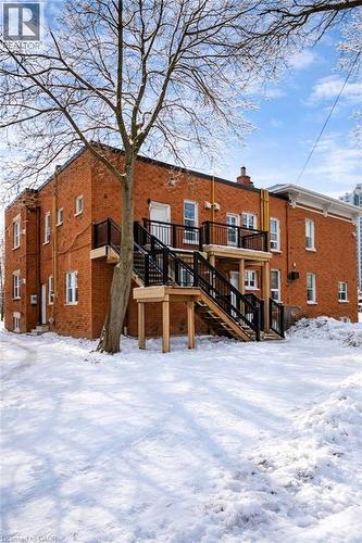 Snow covered rear of property featuring stairs, a deck, brick siding, and a chimney - 46 College Street, Kitchener, ON - Outdoor