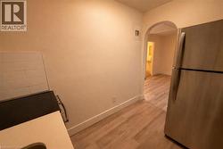 Kitchen with freestanding refrigerator, arched walkways, light wood-style floors, and range with electric cooktop - 