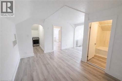 Unfurnished living room featuring light wood-type flooring, arched walkways, and radiator heating unit - 44 Weber Street W, Kitchener, ON - Indoor Photo Showing Other Room