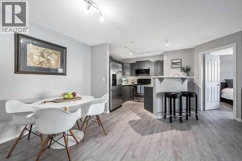 Dining Area and Kitchen with Breakfast Bar - 1120, 4975 130 Avenue Se, Calgary, AB - Indoor Photo Showing Dining Room