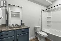 The lower-level bathroom features modern finishes with a tub-shower combination and a stylish vanity - 
