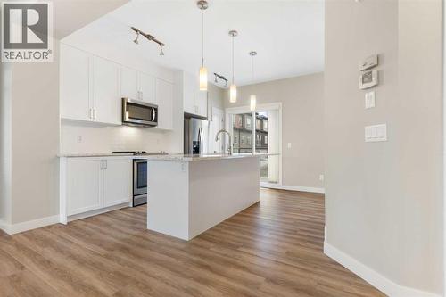 Kitchen, quartz counters, tall upper cabinets, large island with breakfast bar, pendant and track lighting - 217 Sage Bluff Drive Nw, Calgary, AB - Indoor Photo Showing Kitchen With Upgraded Kitchen