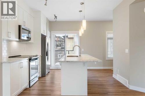 Kitchen with door to balcony in the background - 217 Sage Bluff Drive Nw, Calgary, AB - Indoor Photo Showing Kitchen With Upgraded Kitchen