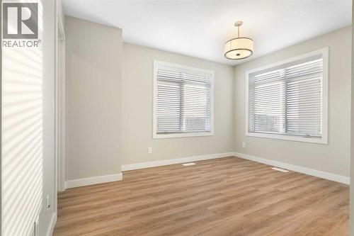 Front primary bedroom, vinyl plank flooring, 2 large windows - 217 Sage Bluff Drive Nw, Calgary, AB - Indoor Photo Showing Other Room