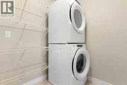 Upper level laundry room, ceramic tile floor, full size front loading washer/dryer, shelving and storage space - 