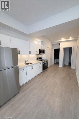 Kitchen with stainless steel appliances, white cabinetry, light wood-type flooring, and decorative backsplash - 228 Margaret Avenue, Kitchener, ON - Indoor Photo Showing Kitchen