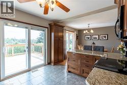 Kitchen featuring a peninsula, black appliances, light stone countertops, pendant lighting, and ceiling fan - 