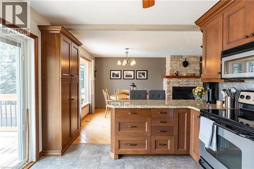 Kitchen featuring stainless steel appliances, brown cabinetry, hanging light fixtures, a chandelier, and light stone countertops - 29 Armstrong Crescent, Grey Highlands, ON - Indoor Photo Showing Kitchen