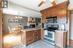 Kitchen with a chandelier, appliances with stainless steel finishes, a peninsula, and light stone counters - 