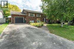 View of front facade featuring a garage, driveway, and brick siding - 