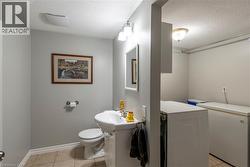 Half bathroom with a textured ceiling, light tile patterned floors, and washing machine and dryer - 