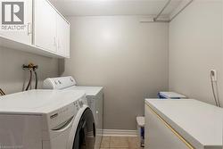 Washroom with a textured ceiling, washer and dryer, light tile patterned floors, and cabinet space - 