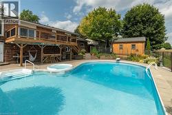 View of swimming pool with a patio area, stairway, an outbuilding, a wooden deck, and a pool with connected hot tub - 