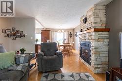 Living area with light wood-type flooring, a fireplace, a textured ceiling, and a chandelier - 