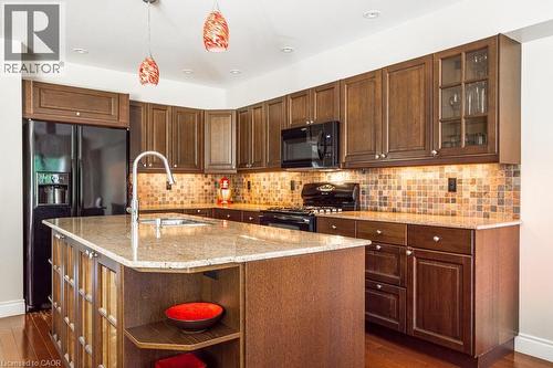 Kitchen with black appliances, a sink, open shelves, dark wood-type flooring, and light stone counters - 330 Strathcona Drive, Burlington, ON - Indoor Photo Showing Kitchen