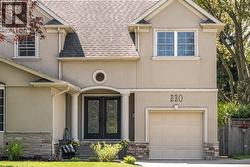 View of front facade featuring a garage, stone siding, fence, and stucco siding - 