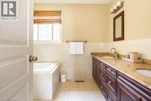 Bathroom with double vanity, a garden tub, tile patterned floors, tile walls, and a wainscoted wall - 330 Strathcona Drive, Burlington, ON - Indoor Photo Showing Bathroom