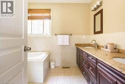 Bathroom with double vanity, a garden tub, tile patterned floors, tile walls, and a wainscoted wall - 