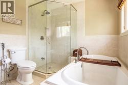 Bathroom with tile walls, a stall shower, a garden tub, toilet, and tile patterned floors - 